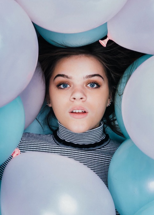 Harper laying down with blue and pink balloons around her head