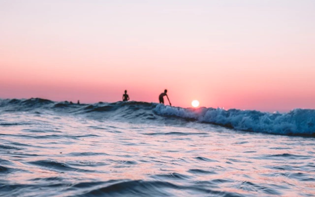 Two people enjoying the sea during sunset